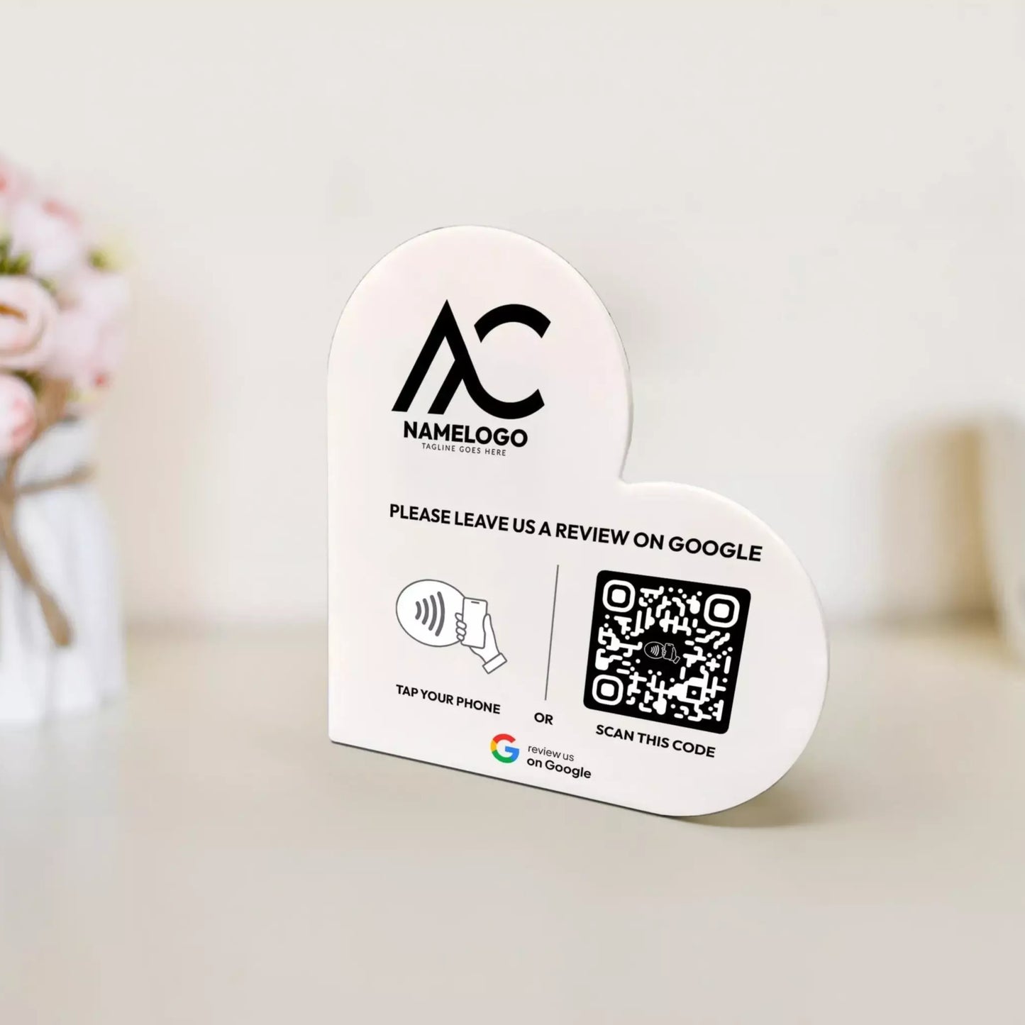 a white sign with a heart shape and a QR code, placed on a table. The sign appears to be a promotional or informational sign, possibly related to a business or service.